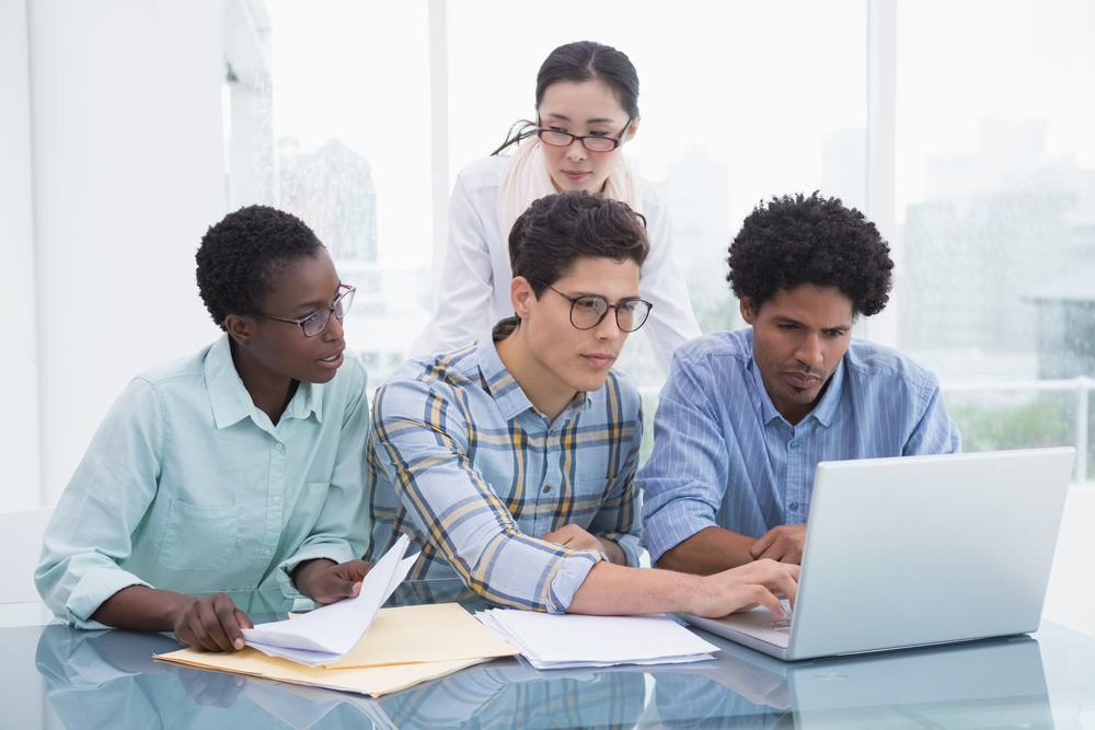 Casual-business-team-working-together-at-desk-in-creative-office - Effective Communication: Teamwork At Its Best
